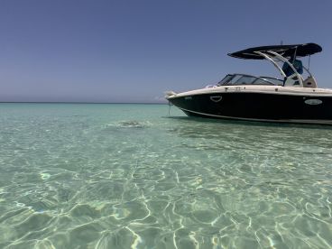 A sleek boat anchored in crystal-clear waters, showcasing the serene beauty of a tropical destination — perfect for leisure and relaxation.
