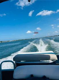 A scenic view from the helm of a speedboat cruising through calm waters, showcasing the beautiful blue sky and shoreline.
