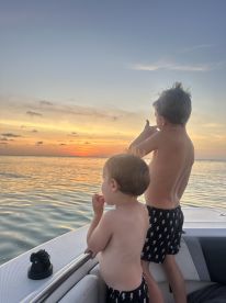 Two children enjoy a beautiful sunset view from the boat, creating a memorable family moment on the water.