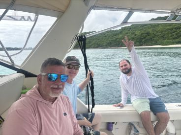 A group of friends enjoys a fun day on the boat, capturing the moment with smiles and peace signs against a scenic backdrop.