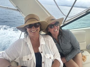 Two friends share a joyful moment aboard a boat, showcasing the fun and camaraderie of a day on the water.