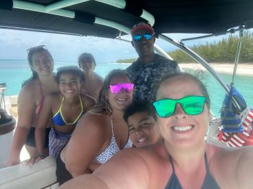 A joyful group of family and friends poses for a selfie aboard a boat, enjoying their time in the beautiful turquoise waters — perfect for memorable adventures on the water.