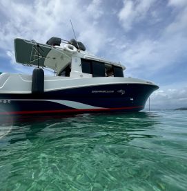 A striking side view of the Barracuda boat gliding through clear turquoise waters, showcasing its sleek design and perfect for aquatic adventures.