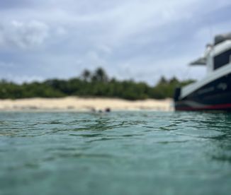 A blurry image captures a boat near a sandy beach, with indistinct figures in the water, creating an unclear scene.