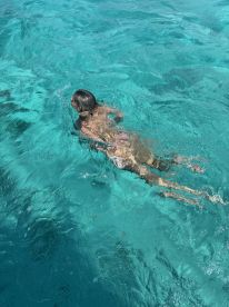 A child swims in crystal-clear turquoise waters, showcasing the beauty of aquatic adventures and family fun in the sun.