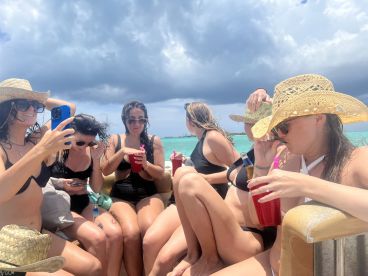 A lively group of friends enjoys drinks and fun on a boat, capturing summer memories under the sun — perfect for a day out on the water.
