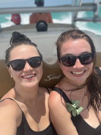 Two friends enjoy a sunny boat ride, smiling and having fun as they cruise through beautiful waters — perfect for memorable adventures on the sea.