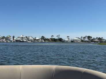 A scenic view of waterfront homes along the coastline, captured from a boat, showcasing the beauty of a tranquil day on the water.