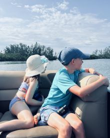 Two children enjoy a scenic boat ride, gazing out at the water and surrounding nature — a perfect moment for family adventures on the water.