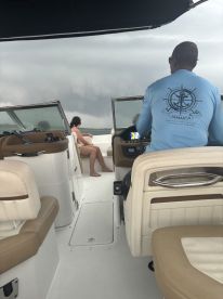Inside view of a boat's helm area, featuring a captain at the controls and a guest relaxing in the seating area — perfect for exploring the waters of Jamaica.