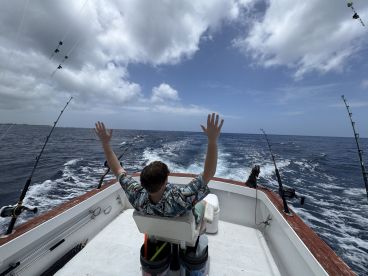 A fisherman enjoys a day out on the ocean, waving from the boat as it cruises through the waves — a perfect scene for fishing enthusiasts.