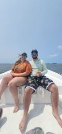 A couple enjoys a sunny day on a boat, relaxing with drinks and soaking up the sun — perfect for a leisurely outing on the water.