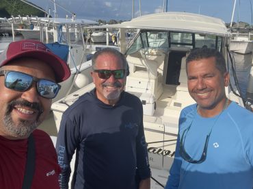 Three friends pose for a cheerful selfie in front of their boat, ready for a day of adventure on the water.