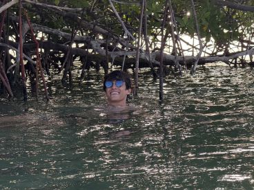 A joyful swimmer enjoys the serene waters among mangroves, capturing the essence of adventure and relaxation in nature.
