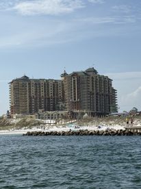 A view of a beachfront high-rise building with people visible on the beach and jetty, but the focus is unclear.
