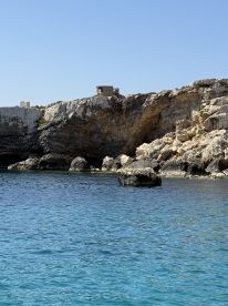 A stunning view of a rocky coastline with crystal-clear waters, showcasing the natural beauty of the area — perfect for scenic boat tours and exploration.