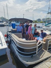A cheerful group poses on a pontoon boat at the marina, ready for a fun day on the water with friends and family.
