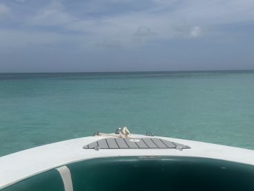 A serene view from the front of a boat, showcasing the calm turquoise waters and clear skies — perfect for a day of relaxation on the water.