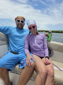 A cheerful couple enjoys a sunny day on the boat, showcasing a perfect moment of relaxation and fun on the water.