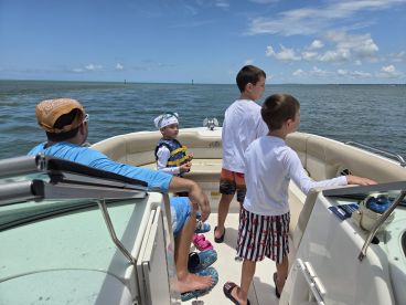 A family enjoys a day on the water, with children exploring the boat and taking in the scenic views — perfect for creating lasting memories on a boating adventure.