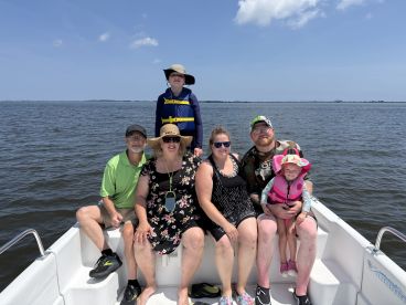 A joyful family poses together on a boat, enjoying a sunny day on the water — perfect for creating lasting memories during summer outings.