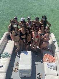 A lively group of friends enjoys a fun day on a pontoon boat, celebrating together in the sun — perfect for bachelorette parties or summer get-togethers.