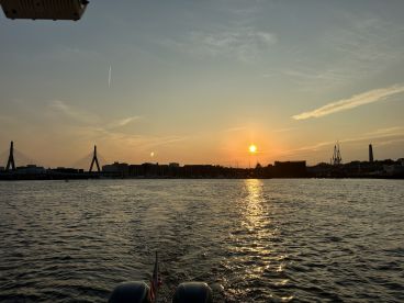 A serene sunset view over the water, showcasing the city skyline and bridges in the background — perfect for evening boat cruises.