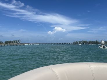 A picturesque view of a serene coastline with a pier and boats in the distance, perfect for showcasing the beauty of a day on the water.