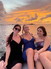 Three friends enjoy a beautiful sunset on a yacht, capturing the perfect moment of friendship and celebration on the water.