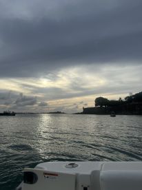 A serene view of a boat's bow with a picturesque backdrop of clouds and a distant shoreline, perfect for capturing the tranquility of a day on the water.