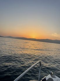 A serene sunset view from a boat, showcasing the tranquil waters and distant mountains — perfect for peaceful evening cruises.