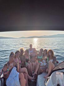 A lively group of friends enjoys a sunset celebration on a boat, complete with drinks and laughter — perfect for unforgettable summer outings.