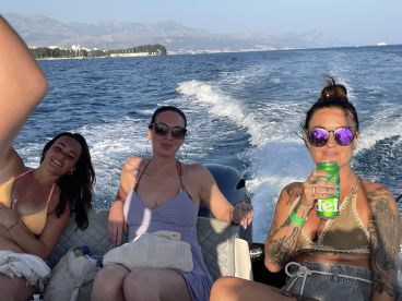 Three friends enjoy a sunny day on a boat, sipping drinks and celebrating together — a perfect moment for summer adventures on the water.