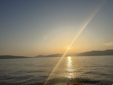 A stunning sunset over the tranquil waters, with silhouettes of distant hills creating a picturesque backdrop — perfect for evening boat trips and scenic views.