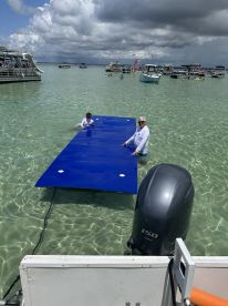 A group enjoys a fun day on the water with a floating mat, showcasing a lively atmosphere perfect for summer adventures.