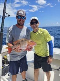 Two anglers proudly display their catch while fishing on a boat, showcasing the excitement of a successful day on the water.