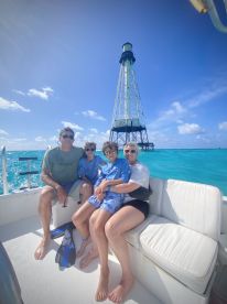 A family enjoys a day on the water near a lighthouse, capturing a memorable moment aboard their boat — perfect for snorkeling adventures and family outings.