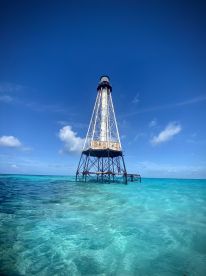 A striking view of a lighthouse standing tall in clear turquoise waters, showcasing the beauty of coastal landmarks.