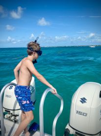 A young boy prepares to snorkel in the vibrant turquoise waters, showcasing the excitement of ocean adventures and water activities.