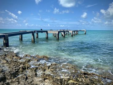 A scenic view of a pier extending into turquoise waters, surrounded by rocky shoreline. Ideal for capturing coastal beauty and serene landscapes.
