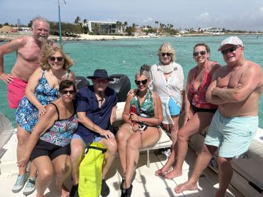 A cheerful group of friends poses for a photo on a boat, enjoying their time together in the beautiful turquoise waters — perfect for memorable celebrations and outings.