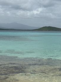 A stunning view of turquoise waters and a lush island backdrop, perfect for showcasing the natural beauty of coastal destinations.