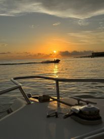 A thrilling sunset scene captures a jet ski rider enjoying the waves, with the sun setting beautifully on the horizon — perfect for adventure seekers and sunset lovers.