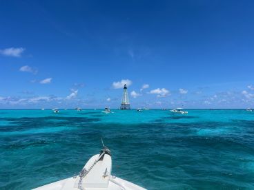 A stunning view of multiple boats navigating through crystal-clear turquoise waters, with a lighthouse in the background — a perfect representation of a vibrant boating destination.