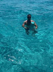 A man enjoys a refreshing swim in crystal-clear turquoise waters, showcasing the perfect setting for aquatic adventures.