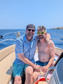 A joyful couple enjoys drinks together on a boat, capturing a perfect moment of celebration and relaxation on the water.