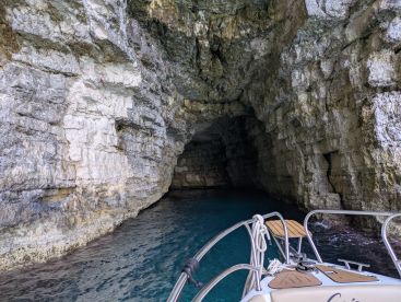 A stunning view of a boat entering a natural cave, showcasing the beautiful rock formations and clear waters — a perfect spot for exploration and adventure.