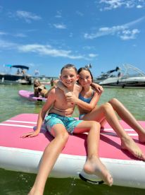 Two kids enjoy a sunny day on an inflatable mat in the water, capturing the joy of summer fun and water activities.