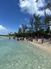 A lively group enjoys a sunny day at the beach, wading in the clear waters and soaking up the sun — perfect for a fun-filled day of relaxation and enjoyment.