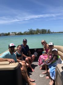 A joyful family enjoys a sunny day on a pontoon boat, creating lasting memories on the water with laughter and fun.